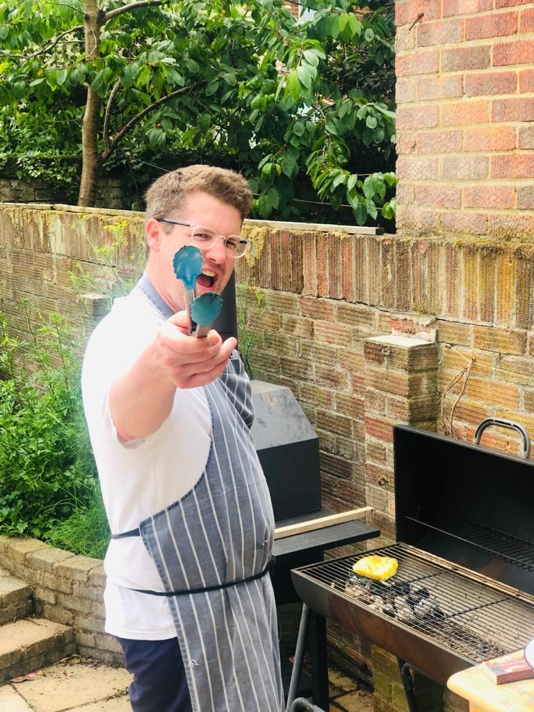 John at a barbecue in a garden, tongs in hand