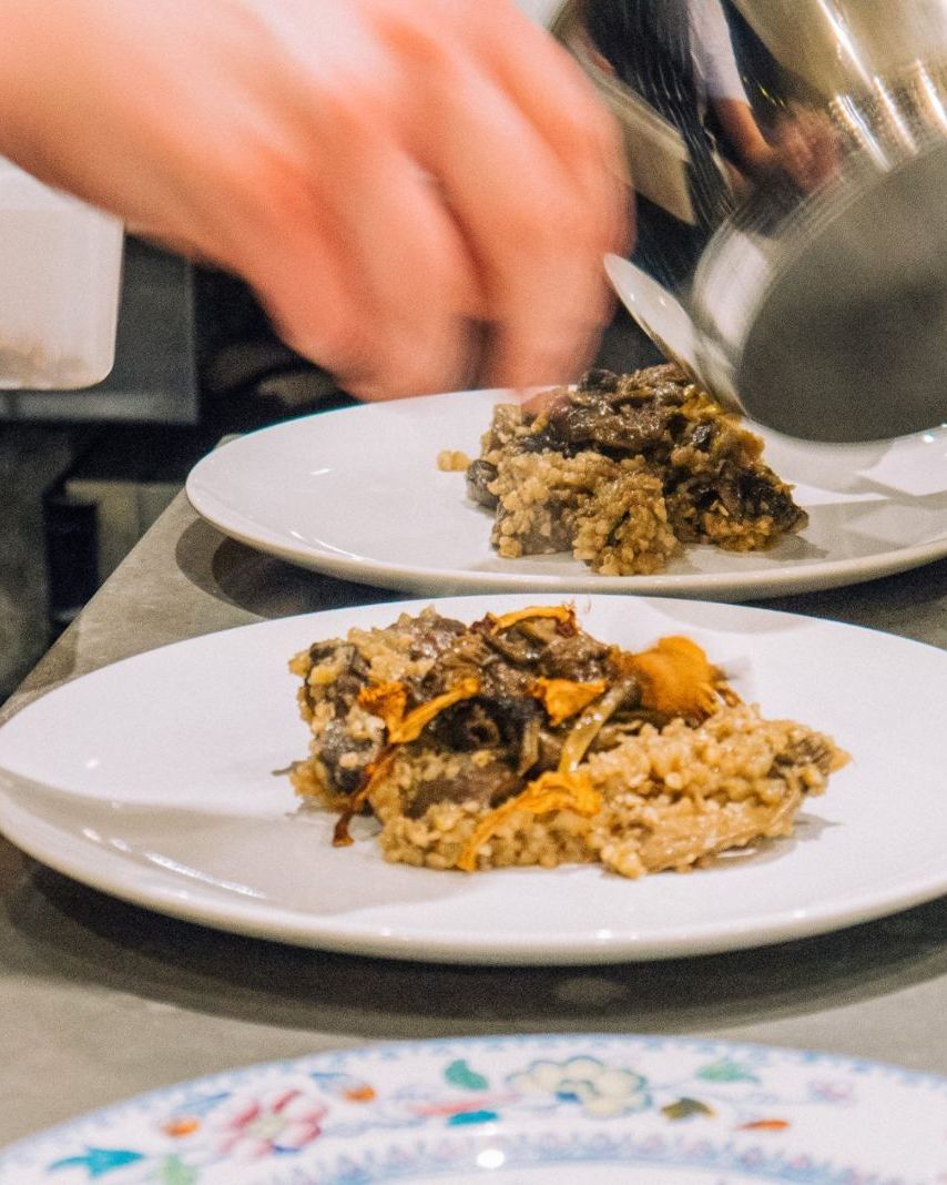 Wild mushrooms and grains being plated at a private dinner