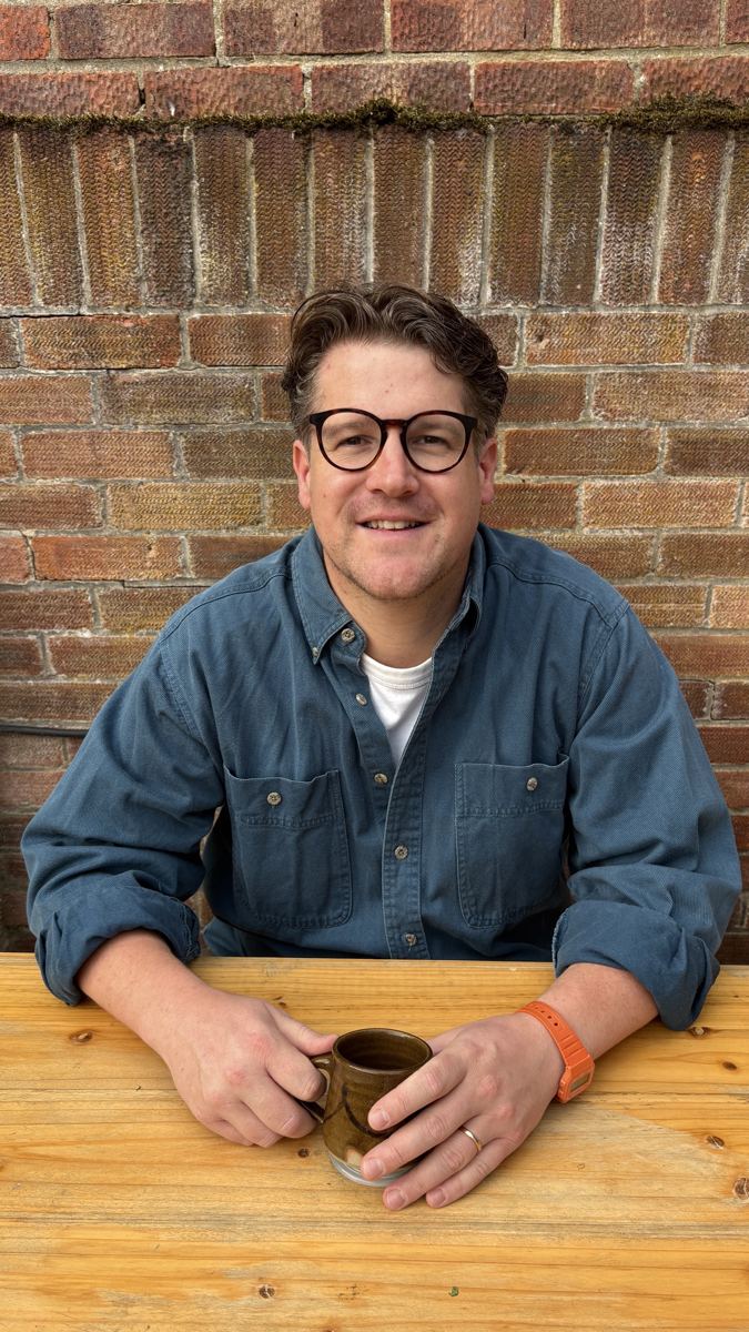 John Magee, private chef, smiling at a wooden table